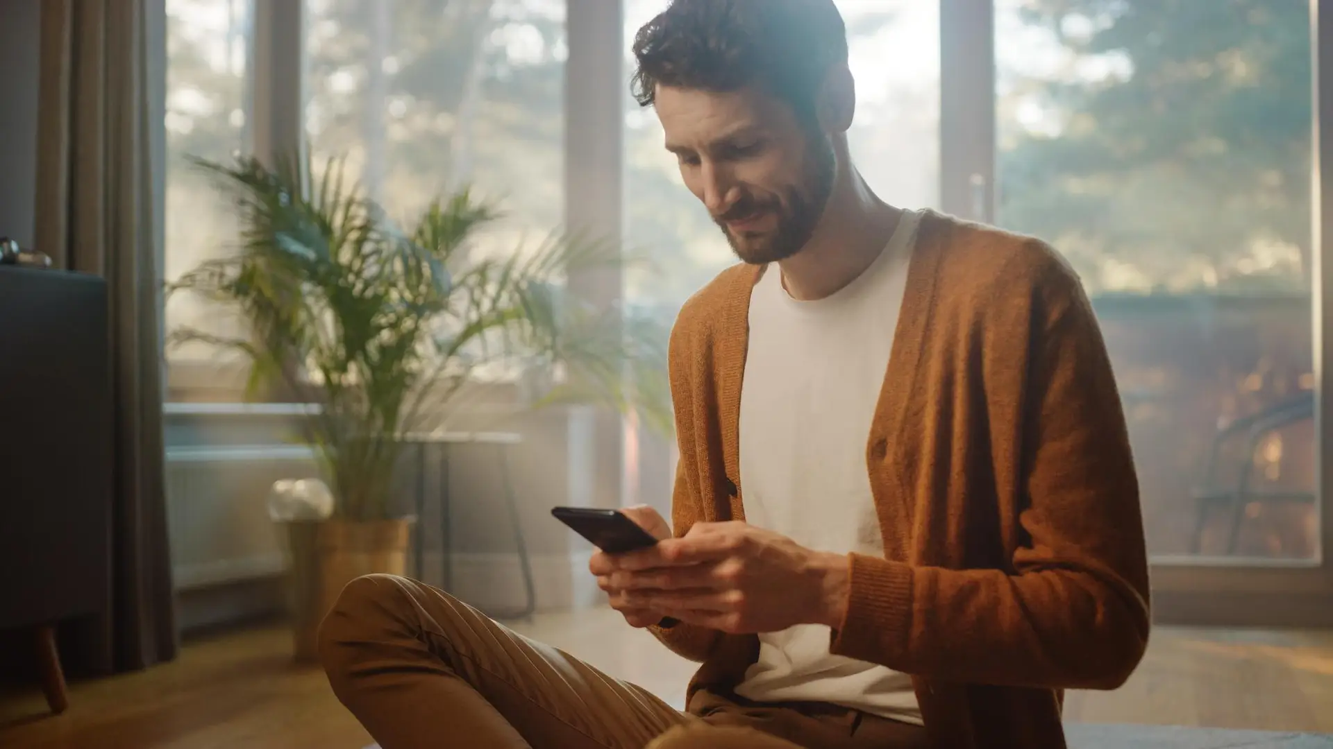 Un chico joven revisando en su móvil la oferta de cuentas bancarias de b100. Un chico joven revisando en su móvil la oferta de cuentas bancarias de b100.
