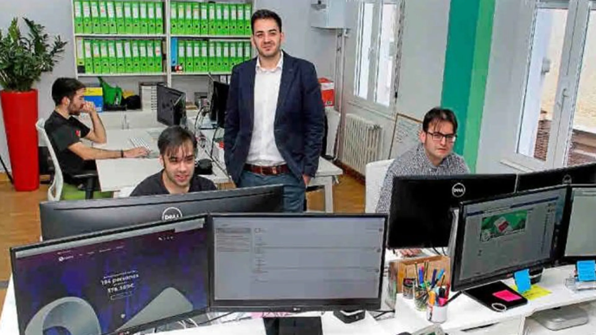 Eduardo Delgado, junto a tres compañeros que trabajan frente a varios monitores en la oficina de Roams.