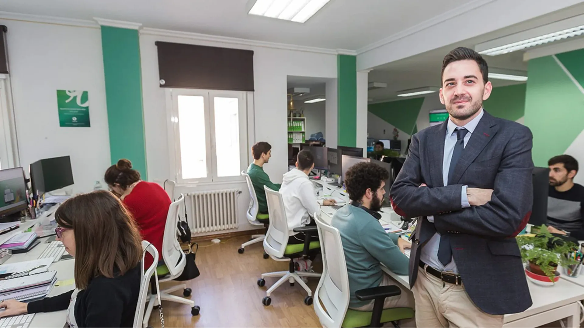 Eduardo Delgado posa en la oficina de Roams mientras varios empleados trabajan detrás.