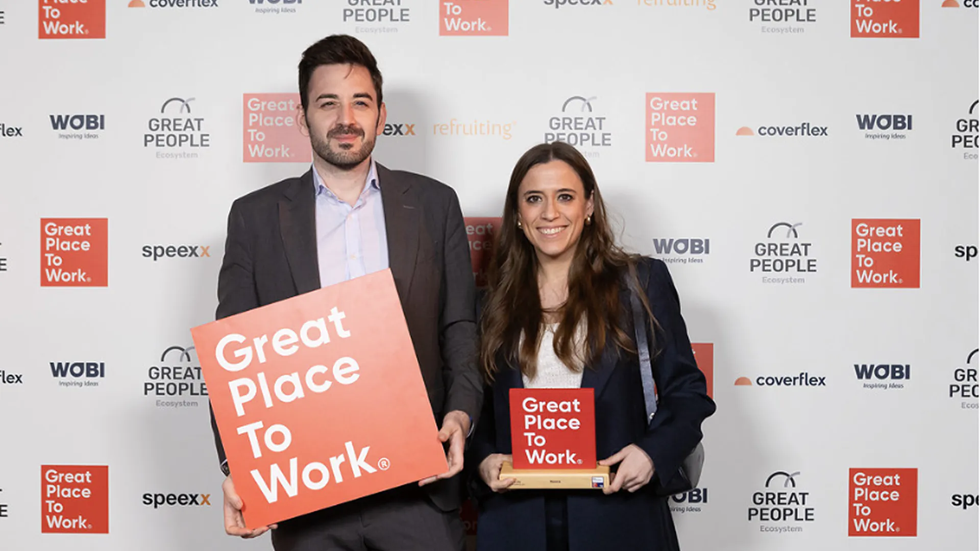 Eduardo Delgado y Beatriz Gallinas posan en un photocall con un cartel y un trofeo de Great Place to Work.