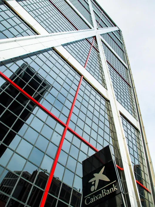 Fachada de un edificio moderno de CaixaBank con estructura de vidrio y el logotipo visible.