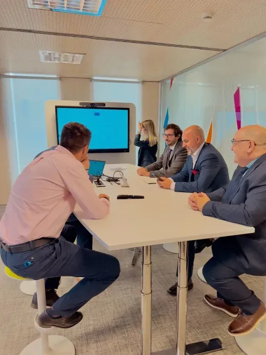 Equipo de directivos en una sala de reuniones con pantalla interactiva. Colaboración y estrategia en un entorno de trabajo moderno.
