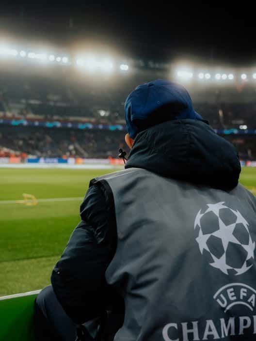 Empleado de la UEFA sentado en el borde del campo durante un partido de la Champions League.