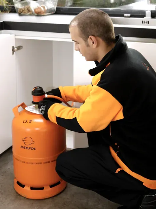 Técnico revisando una bombona de gas butano Repsol en una vivienda.