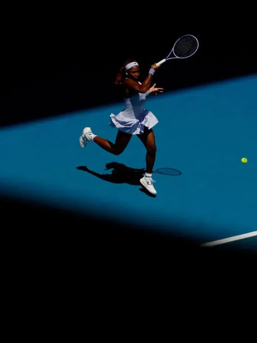 Tenista profesional ejecutando un golpe de derecha en una pista azul durante un partido de tenis