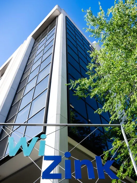 Fachada del edificio de oficinas de WiZink con su logotipo en primer plano bajo un cielo azul.
