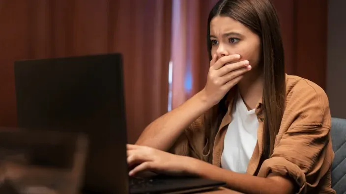 Mujer asustada frente a un portátil, representando los peligros en internet.