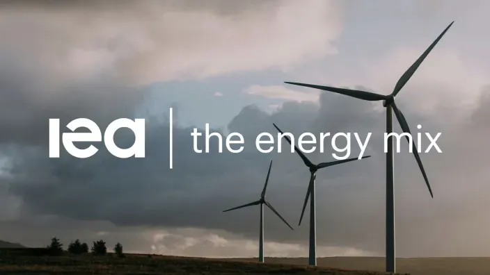Molinos de viento en un paisaje nublado junto al logotipo de la Agencia Internacional de la Energía (IEA).