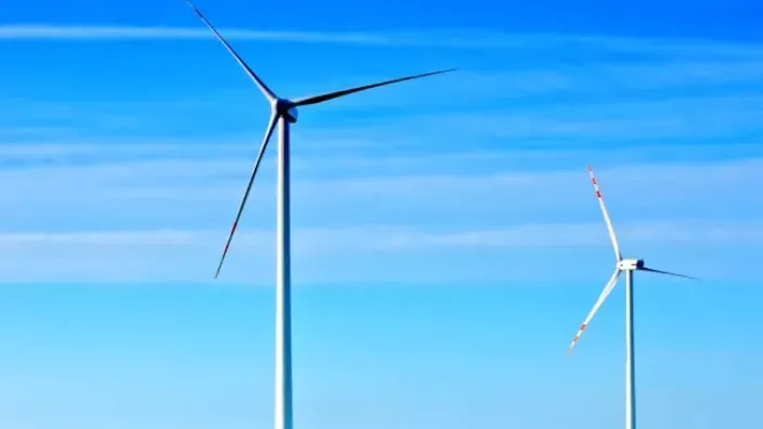 Aerogeneradores en funcionamiento sobre un campo verde con cielo despejado.
