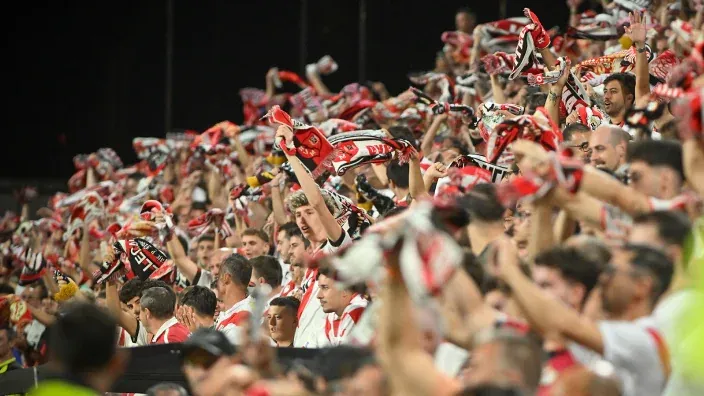 Aficionados del Rayo Vallecano celebrando en la grada con bufandas durante un partido