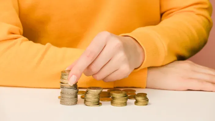 Persona apilando monedas de euro para representar el ahorro y la gestión de la economía doméstica.