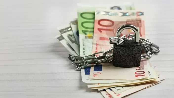 Billetes de euro protegidos por una cadena y un candado para representar la seguridad financiera y el ahorro.