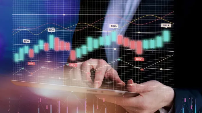 Inversor analizando gráficos financieros de bolsa en una tablet con indicadores de trading buy y sell.