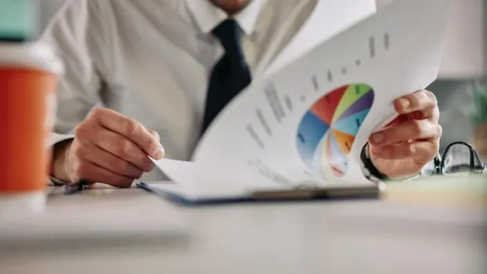 Asesor financiero analizando la rentabilidad de una cartera de inversión en un informe con gráficos.