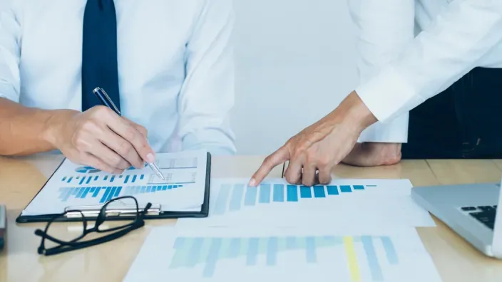 Expertos financieros analizando gráficos de crecimiento y rentabilidad en una oficina durante una reunión.