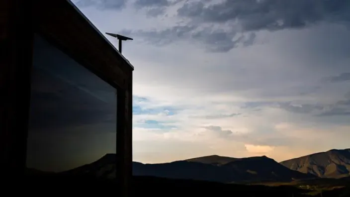 Antena de Starlink instalada en el tejado de una vivienda con vistas a un paisaje montañoso al atardecer.