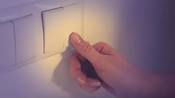 Mano apagando un interruptor de luz en casa para ahorrar electricidad.