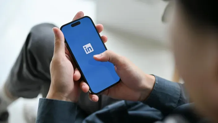 Usuario utilizando la aplicación de LinkedIn en un smartphone desde casa