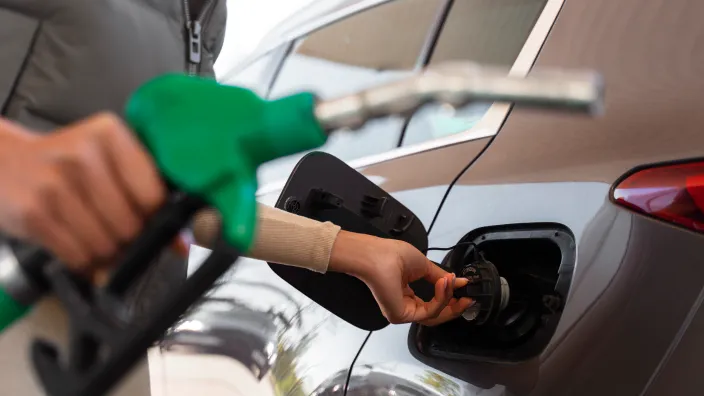 Persona introduciendo la manguera de combustible en el depósito de un coche.