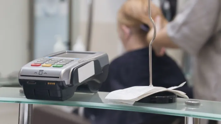 Terminal de pago con tarjeta junto a un bloc de recibos en un mostrador de comercio.