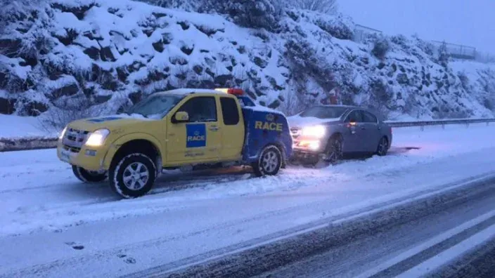 Camión de asistencia RACE remolca un coche averiado en una carretera cubierta de nieve
