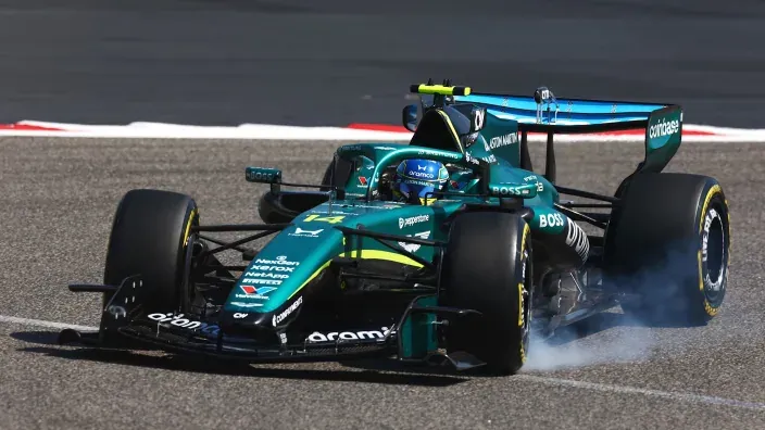 Monoplaza de Aston Martin durante una sesión en circuito con humo saliendo de los neumáticos traseros.