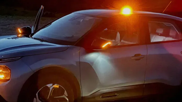 Coche detenido con la baliza V16 Help Flash encendida sobre el techo, emitiendo luz de emergencia naranja durante la noche