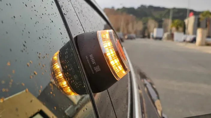 Baliza V16 adherida a la ventanilla de un coche en un día lluvioso.