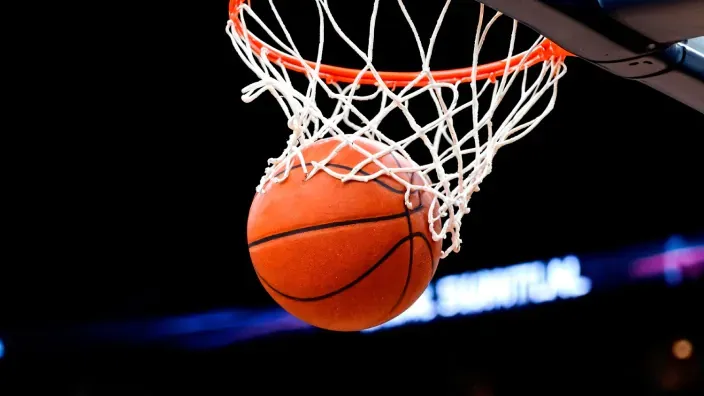 Balón de baloncesto atravesando la red de la canasta durante un partido.