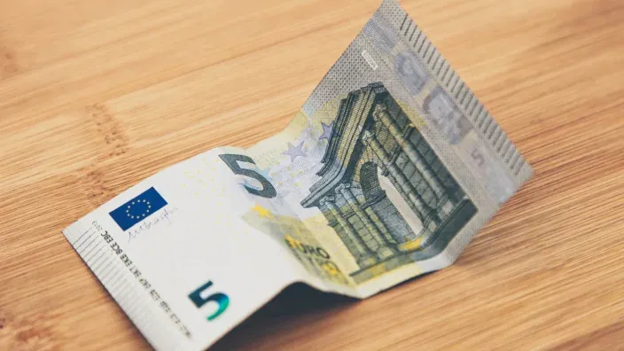 Billete de cinco euros doblado sobre una superficie de madera.
