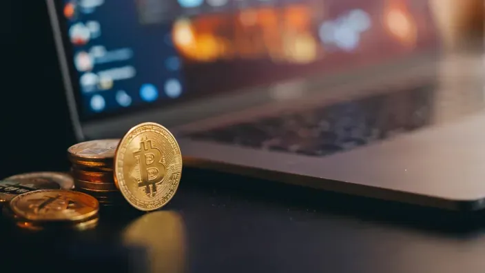 Monedas de Bitcoin junto a un portátil representando inversión en criptomonedas