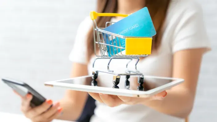 Concepto de finaciación de compra con tarjeta de crédito azul en un carrito sobre una tablet.