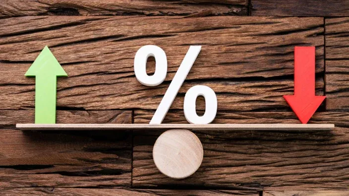 Símbolo de porcentaje en balanza con flechas de subida y bajada sobre fluctuación de precios.