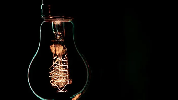Bombilla encendida sobre fondo oscuro, símbolo de suministro eléctrico e iluminación.