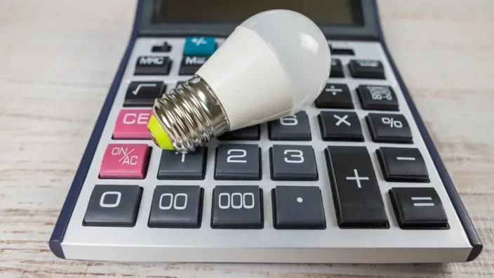 Bombilla LED colocada sobre una calculadora, símbolo del ahorro en la factura de la luz