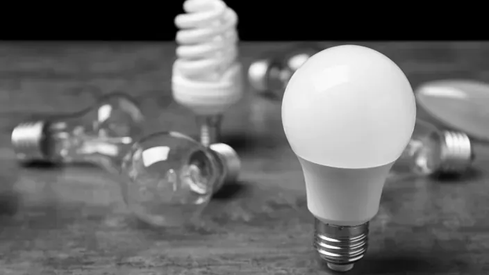 Bombillas de distintos tipos sobre una superficie con una bombilla led en primer plano