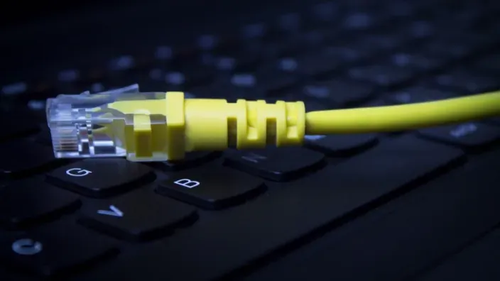Cable Ethernet amarillo sobre un teclado de ordenador, simbolizando la conexión de internet de alta velocidad.