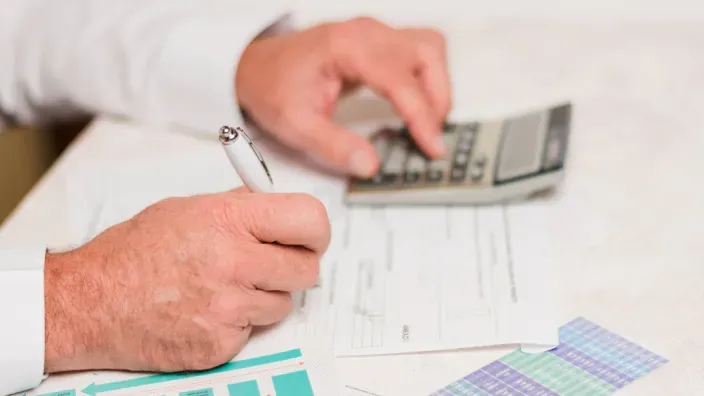 Persona calculando inversión con una calculadora para el control de las finanzas.