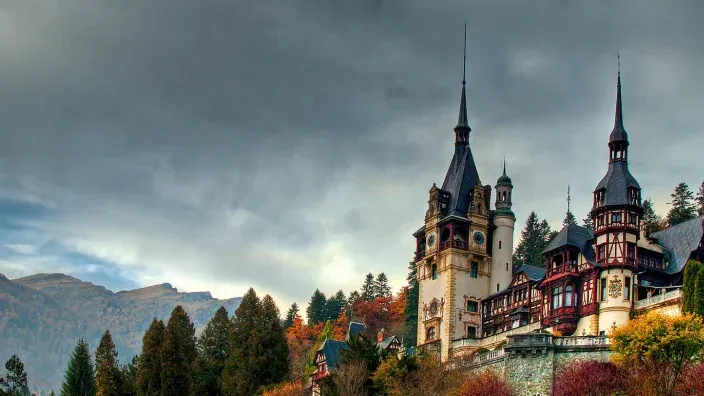 Vista del castillo de Peleș en Rumanía rodeado de árboles en otoño.