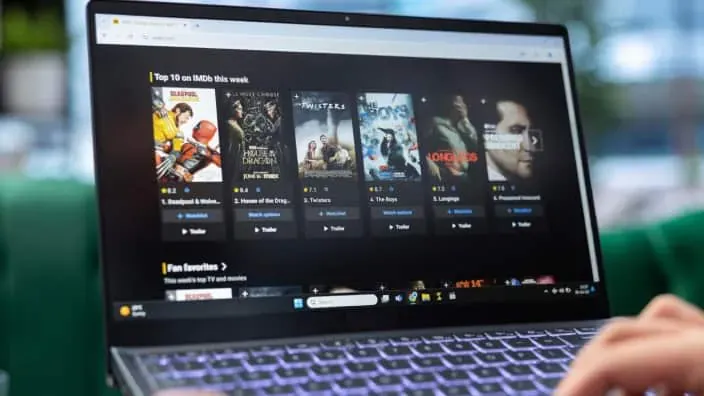 Persona navegando en un portátil por el catálogo de series y películas de una plataforma de streaming.