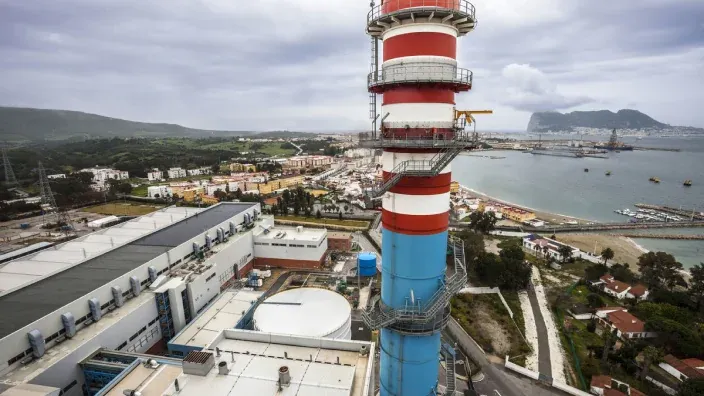 Central térmica con gran chimenea industrial ubicada cerca de la costa