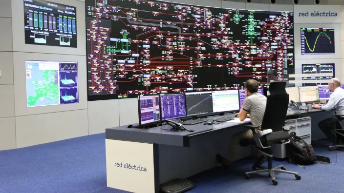 Sala de control de Red Eléctrica con pantallas de supervisión y técnicos monitorizando el sistema eléctrico nacional.