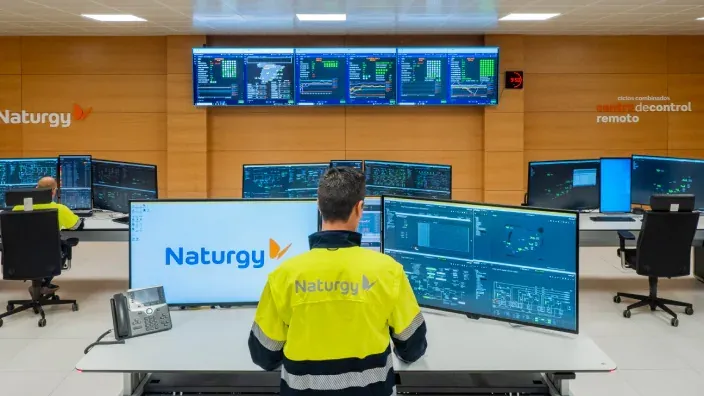 Trabajador en un centro de control de Naturgy rodeado de pantallas.