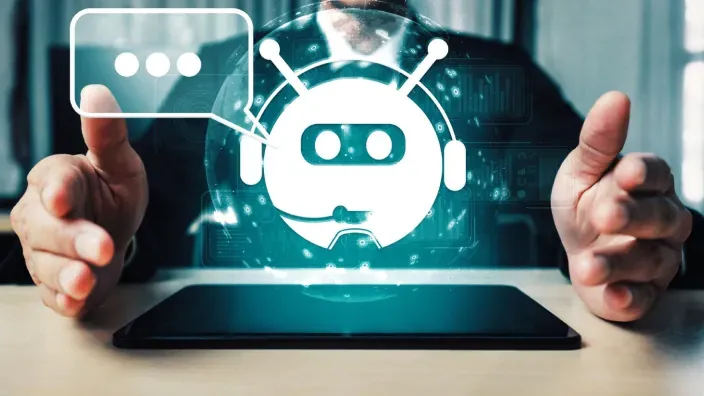 Icono de chatbot con inteligencia artificial emergiendo de una tablet en manos de un usuario.
