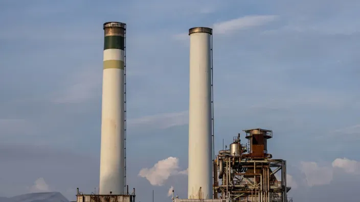 Dos grandes chimeneas blancas de una central nuclear industrial bajo un cielo parcialmente nublado.