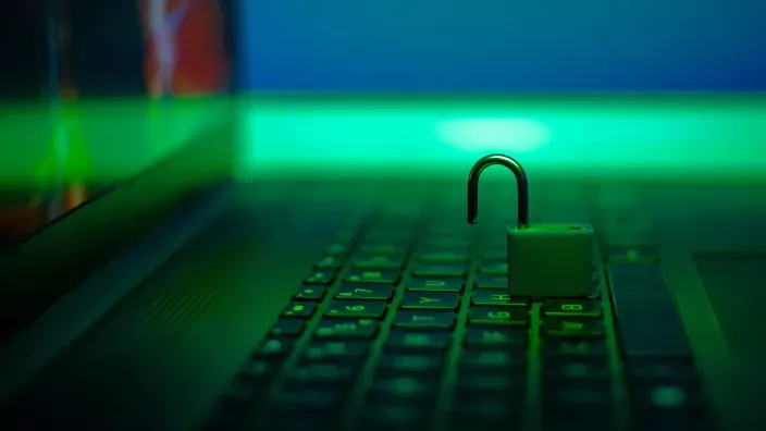 Candado abierto sobre un teclado de portátil simbolizando ciberseguridad o una brecha de datos digitales.