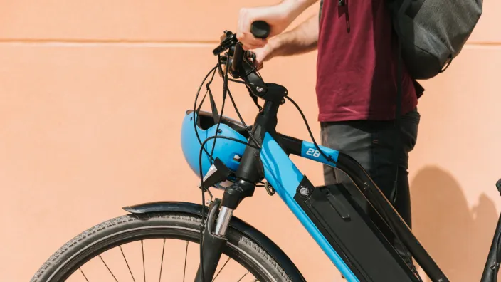 Persona junto a una bicicleta eléctrica azul, un medio de transporte sostenible y una alternativa de movilidad urbana.