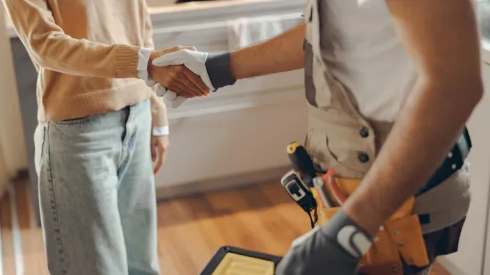 Cliente estrechando la mano a un reparador en el hogar con guantes de trabajo