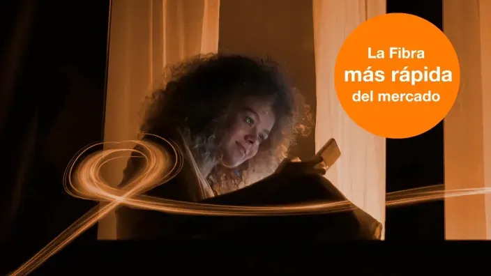 Anuncio de Orange La Fibra más rápida del mercado con mujer joven usando móvil en casa.