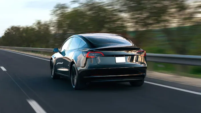 Coche eléctrico circulando por una carretera despejada rodeada de naturaleza simbolizando movilidad sostenible y conduccion eficiente.